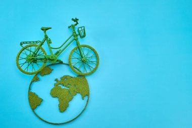 Dünya haritasında yeşil ulaşımı simgeleyen minyatür bir bisiklet..
