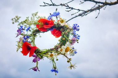 Yaz Gündönümü Günü, Yaz ortası. Putperest cadı gelenekleri. Canlı kır çiçekleri bulutlu bir arka planda çelenk oluşturuyor..