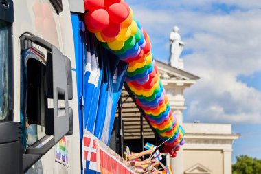 Mavi gökyüzünün altındaki tarihi binanın önünde gökkuşağı balonlarıyla renkli geçit töreni..