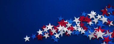 Koyu mavi arka planda kırmızı, beyaz ve mavi parlayan yıldızların dağınık dizilişi, şenlikli ve kutlamalı bir atmosferi çağrıştırıyor..