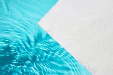 Işığı yansıtan dalgalı suyla bir havuz kenarı gösteren minimalist görüntü.