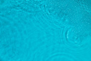 Canlı mavi bir su yüzeyindeki kabarcıkların ve kabarcıkların yakın çekimi.