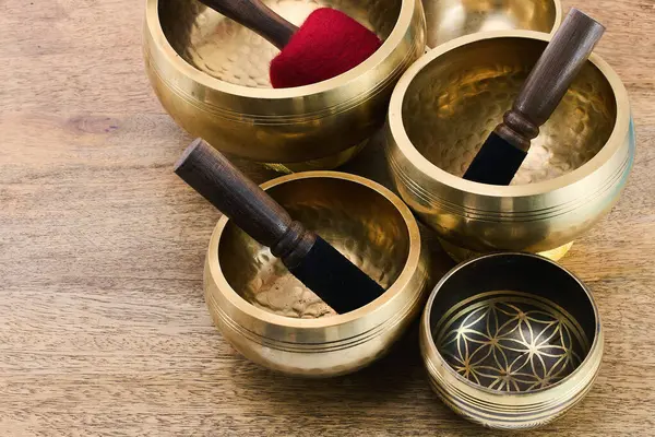 Tahta bir yüzey üzerinde tokmak bulunan Tibet şarkı kaseleri koleksiyonu, sakin ve geleneksel bir ortam sergiliyor..