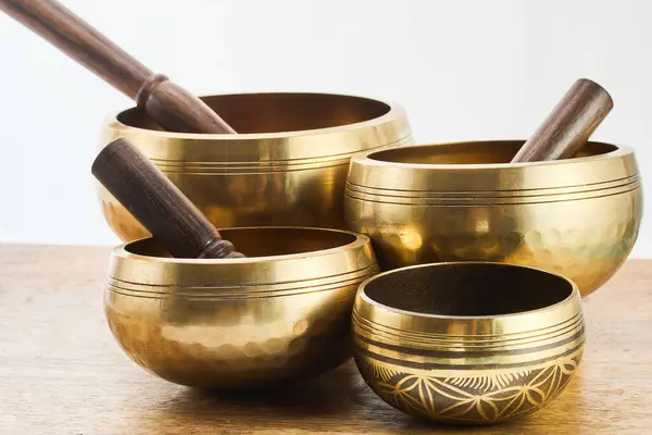 stock image Close-up of golden metal singing bowls with wooden mallets on a wooden surface.