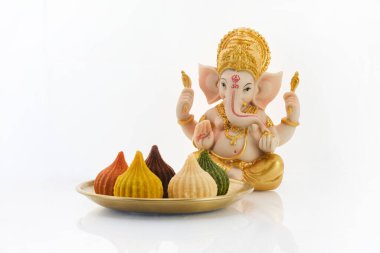 Tanrı Ganesha 'nın heykeli. Huzurlu bir ortamda renkli modak şekerlerle dolu bir tabak..