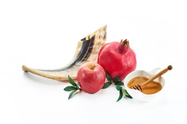 Geleneksel Rosh Hashanah sembolleri elma, bal, nar ve beyaz arka planda bir shofar boynuzu..