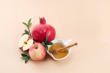Rosh Hashanah için bej arka planda bal, nar ve elma içeren durgun bir yaşam düzeni..