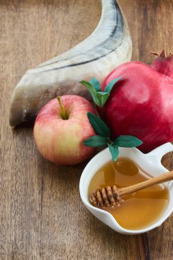 Traditional symbols of Rosh Hashanah featuring apple, pomegranate, honey, and shofar on wooden background. clipart