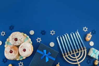 Yahudi bayramı Hannuka konsepti. Geleneksel reçelli çörekler ve koyu mavi arka planda menorah çerçevesi.