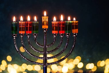 Hanukkah Menorah with burning candles on dark background with bokeh lights clipart