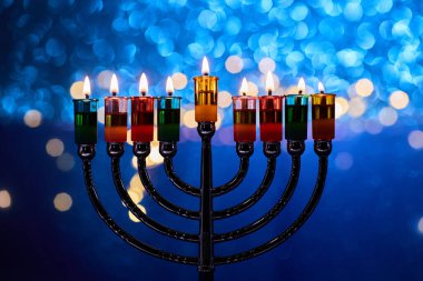 Hanukkah Menorah with burning candles on dark background with bokeh lights clipart