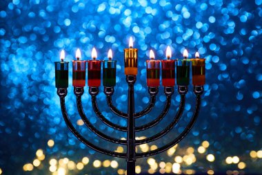 Hanukkah Menorah with burning candles on dark background with bokeh lights clipart