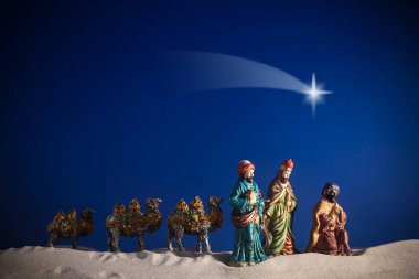 Depiction of Three Wise Men and camels under a bright star in a desert setting. clipart