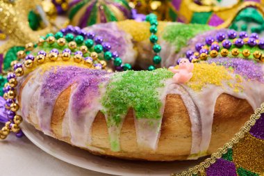 Rengarenk boncuklarla süslenmiş canlı bir Kral Pastası. Üstüne de krema konmuş Mardi Gras şenlikleri..