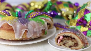 Mardi Gras boncukları ve bebek heykelciğiyle bezenmiş renkli bir Kral Pastası. Canlı yeşil, mor ve altın rengi..