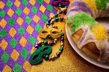 Colorful Mardi Gras setup with beads, masks, and a king cake on a festive background. clipart