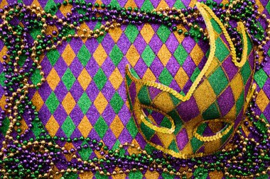 Parlak Mardi Gras maskesi boncuklu kolyeler ve altın, mor ve yeşil renkli desenler..