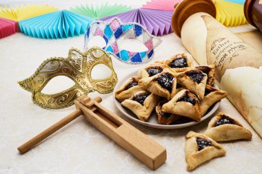 Renkli Purim sahnesi bir desenli yüzey üzerinde maskeler, içiciler ve hamantaschen.