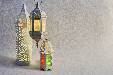 Arkaplanda parlayan ışıkları olan üç tane karmaşık şekilde tasarlanmış fener..