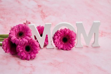 Beyaz harfler annemin pembe çiçekli mermer arkaplanını gösteriyor..
