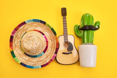 Renkli sombrero, gitar ve parlak sarı arka planda bıyıklı kaktüs..