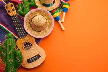 Turuncu arka planda şapka, marakas ve gitarla Meksika temalı renkli bir set..