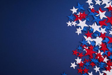 Kırmızı, beyaz ve mavi yıldızlar koyu mavi arkaplana dağılmış neşeli bir atmosfer yaratıyorlar..