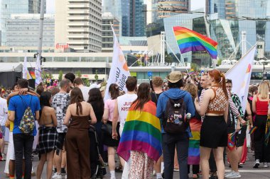 İnsanların çeşitliliği kucakladığı, kentsel bir ortamda bir Onur etkinliğinde gökkuşağı bayrakları taşıdığı canlı bir kutlama..