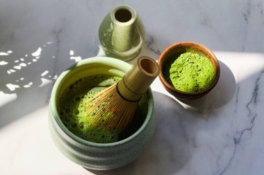 Geleneksel kibrit çay seti toz, bambu çırpısı ve mermer yüzeyde güneş ışığı..