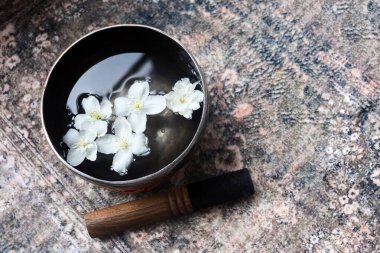 Zarif beyaz çiçekler siyah bir kasede süzülür, rahatlatıcı renklerle sakin bir sahne yaratır..