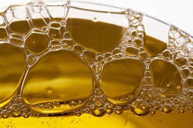 Parlak ve köpüklü bir atmosfer oluşturan, kıvrımlı baloncuklu altın sıvıya yakın çekim.