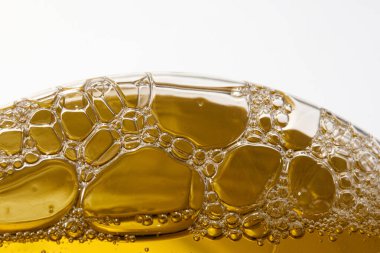 Altın sıvıdaki şeffaf kabarcıkların yakın plan çekimi soyut bir model oluşturur..