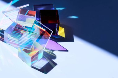 Renkli cam prizmalar beyaz bir yüzeye canlı gölgeler ve yansımalar bırakıyor..