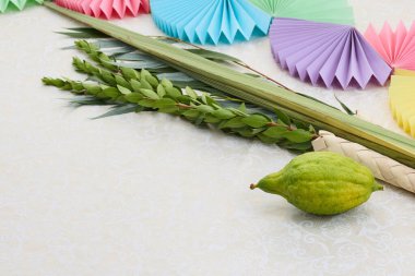 Lulav, etrog ve desenli arka planda canlı kağıt dekorasyonlarıyla şenlikli bir Sukkot düzenlemesi.