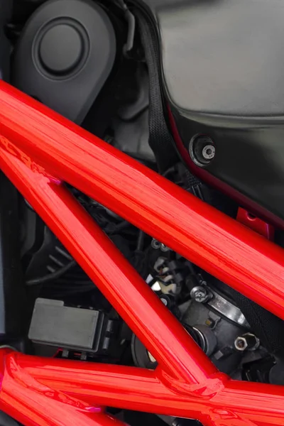 Detail of black motorcycle with red metal protector. Background