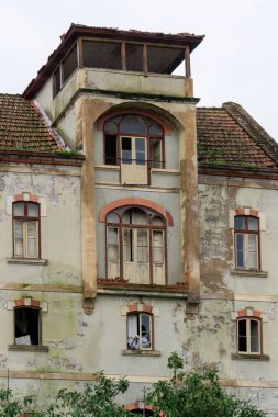 Antique abandoned multi-storey house with tile roof.