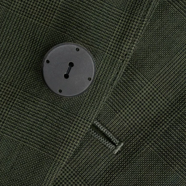 Button on the checkered dark green jacket close up