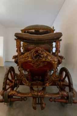 Antique richly decorated wooden red and gold carriage in the museum