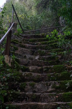 Ancient stone staircase covered with moss with metal railings in the mountains