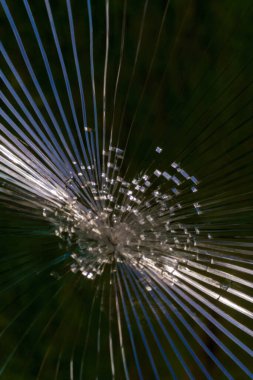 Cracks in the glass at the point of impact. Blue-green background