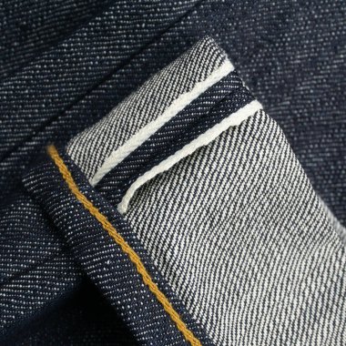 Çiğ kot pantolon yakası, beyaz selvedge arka plan, yakın plan.