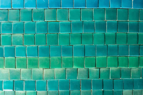 Background of small square tiles in different shades of blue and green close up