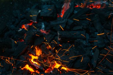 Coals with sparks in a huge old metal grill background