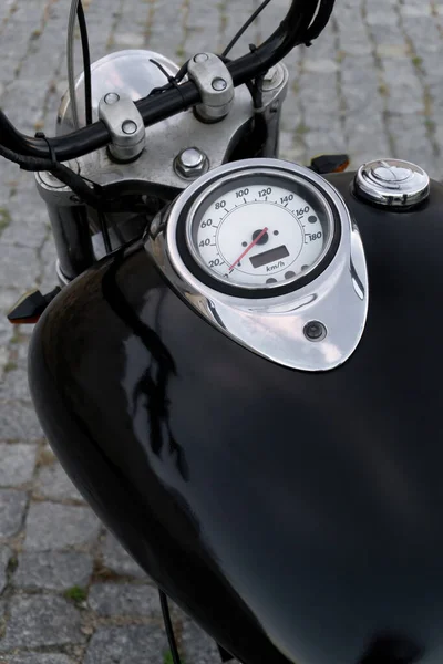 Detail of classic chopper motorcycle black tank with speedometer and chrome details. View from above