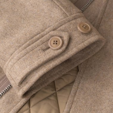 Sleeve of beige woolen coat close up background