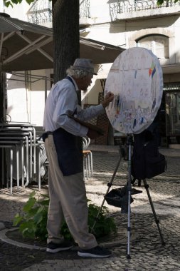 Lizbon, Portekiz. 10.05.2023 Portekiz Lizbon 'un göbeğindeki sokakta resim yapan yaşlı bir sanatçı.
