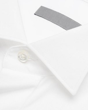 Klasik beyaz gömlek kanat ucu yakalı, üzerinde inci düğmeler var.