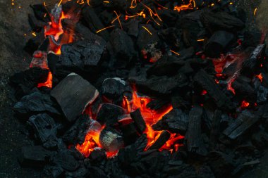 Coals with sparks in a huge old metal grill background