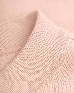 Çıplak pamuklu tişörtün tasmasının bir kısmı, düzgün bir şekilde birleştirilmiş elastik bantla. Doğal, yumuşak ışıklandırma kumaşların dokusunu ve ince tonlarını vurgular, minimalist tasarım ve kalite işçiliğinin altını çizer.