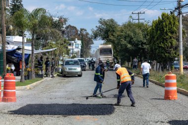 Puebla şehrinin sokaklarında çukurları tamir eden iki işçi..
